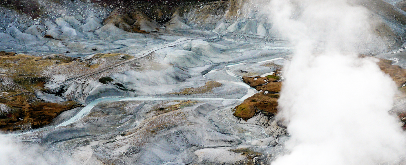 Steaming clouds of water vapor erupt from the ground.